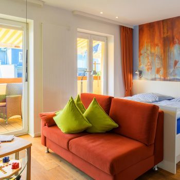 Couch und Bett mit Blick auf Balkon Apartment Kajuete ferienwohnungen